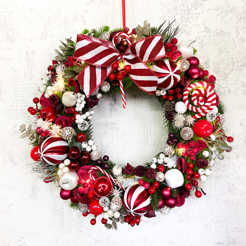 coroniță de Crăciun jucăuș cu acadele in nuanțe de roșu si alb pe suport din brad artificial