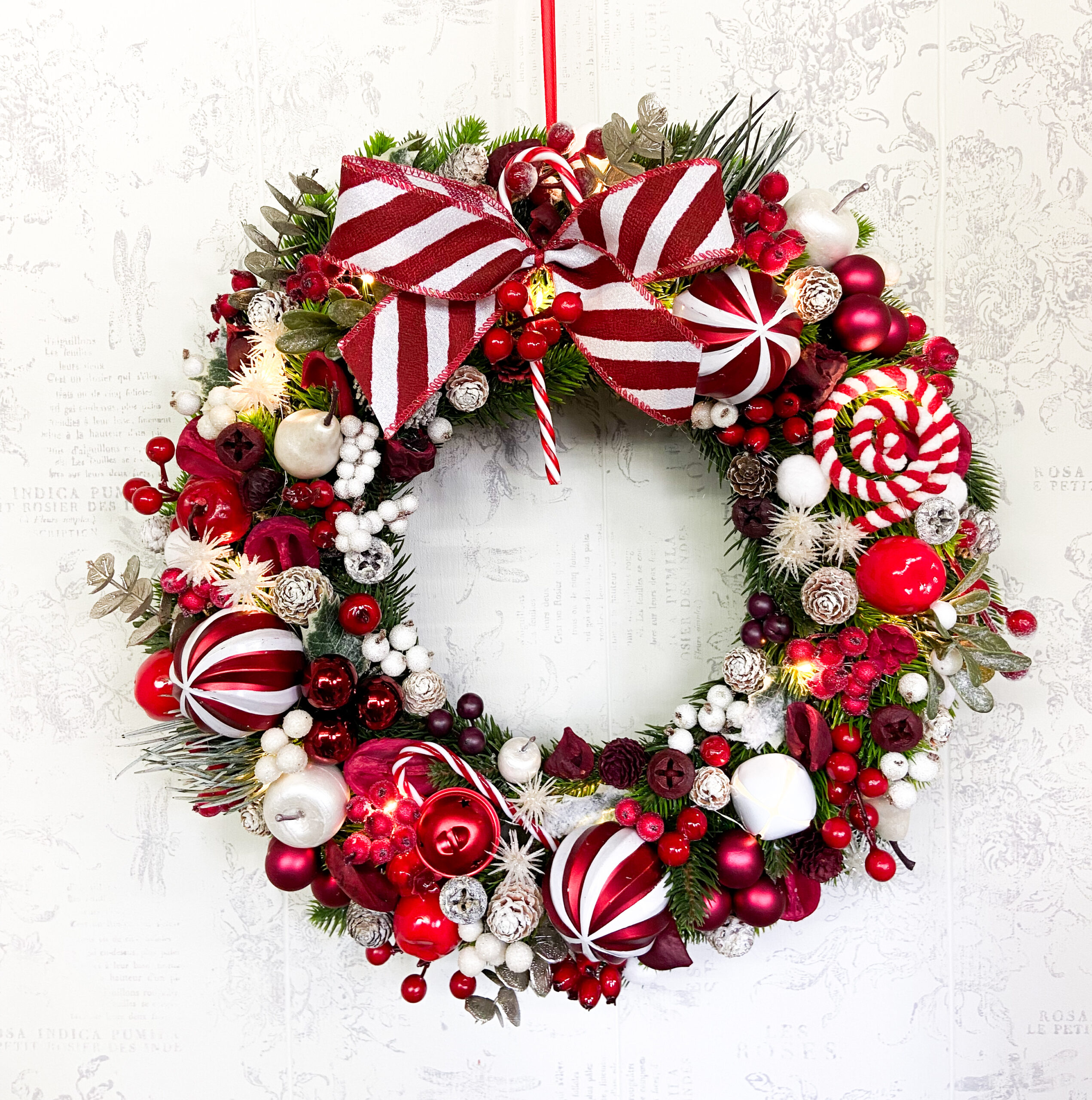 coroniță de Crăciun jucăuș cu acadele in nuanțe de roșu si alb pe suport din brad artificial